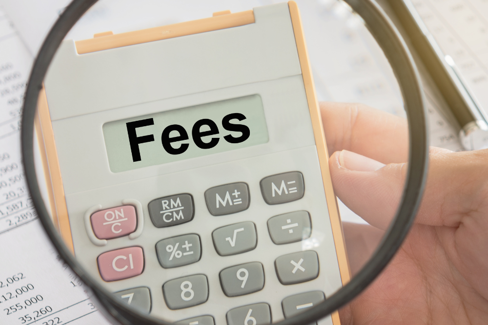 Magnifying glass over calculator labeled fees illustrating how travelers should examine the service fee on Airbnb and VRBO before booking at mystarvr.com.