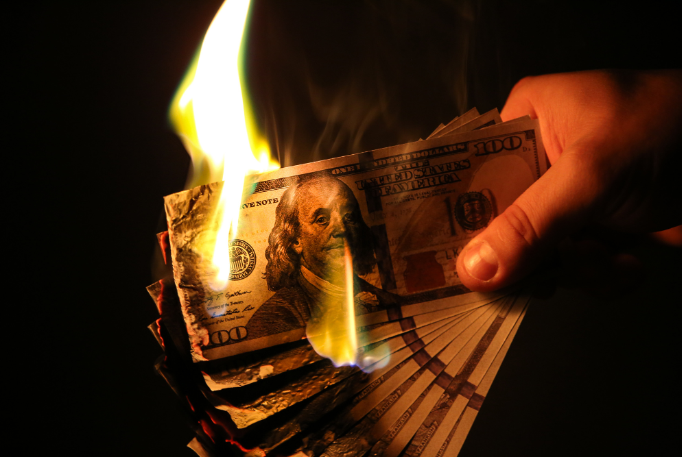 Burning cash symbolizing extra costs and the service fee on Airbnb and VRBO that travelers can avoid by booking direct at mystarvr.com in Kanab Utah.