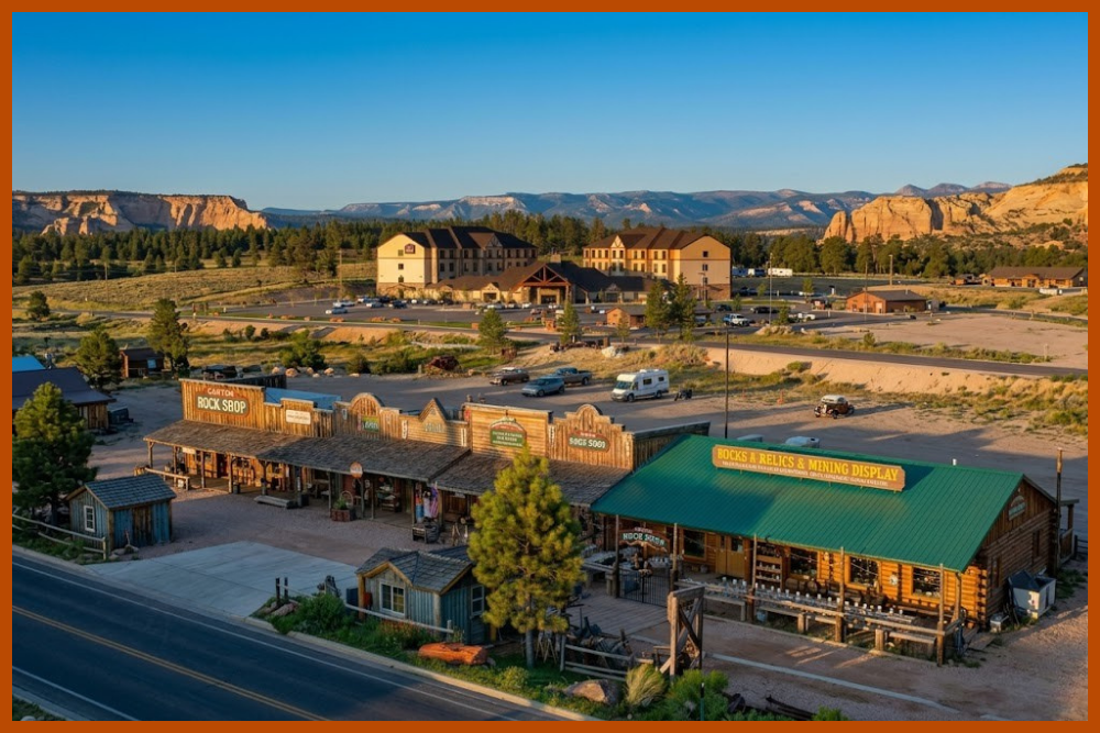 Aerial view of Bryce Canyon City Utah lodging and shops at golden hour, showing the Best Western Ruby's Inn and western style storefronts with red rock cliffs in the background, one of the main gateway towns for visitors looking for where to stay near Bryce Canyon on a southern Utah national parks road trip.